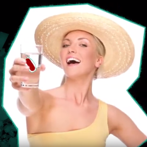 Eine Frau mit einem Hut lacht und hält ein Glass Wasser mit etwas rotem drin hoch